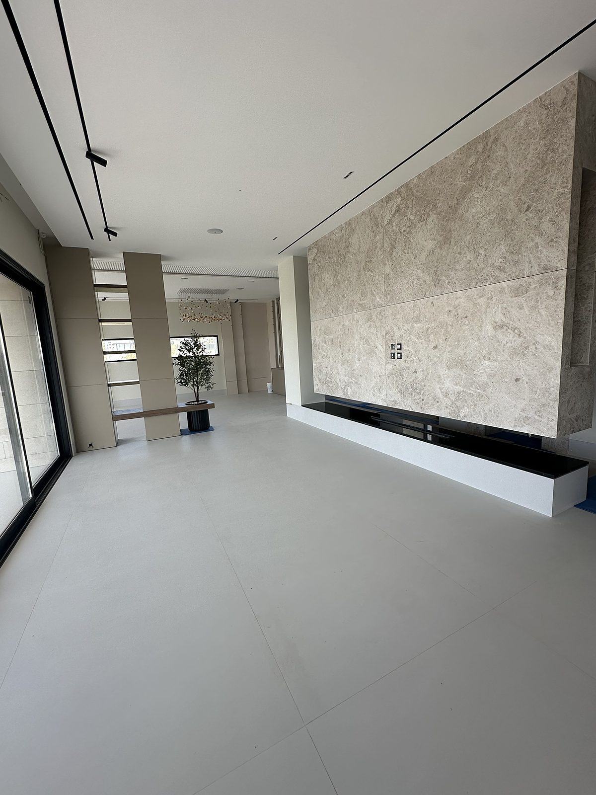 Living room with marble-clad wall and linear lighting